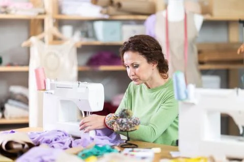 Female tailor using sewing machine to make garment in studio Stock Photos