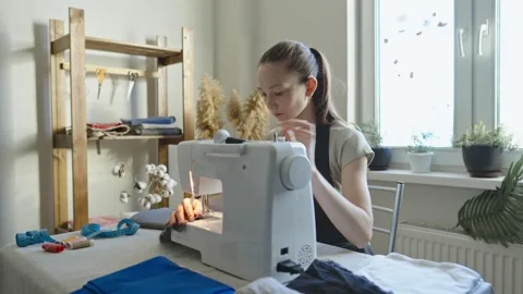 A female tailor is working on a sewing machine stitching fabric Stock Footage 297938354