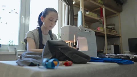 A female tailor is working on a sewing machine stitching fabric Stock Footage 297938948
