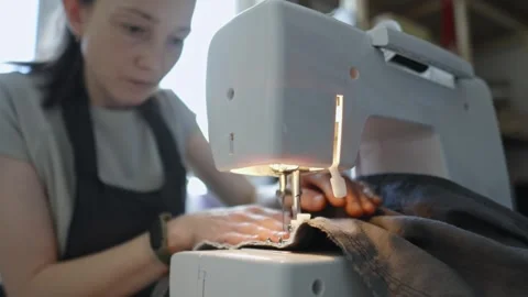 A female tailor is working on a sewing machine stitching fabric Stock Footage 297939042