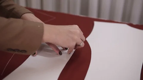 Female tailor is working at table with red cloth in atelier. Skilled seamstress Stock Footage 121504335