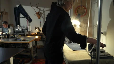 A female tailor working in a workshop repairing old denim clothes Stock Footage 221227770