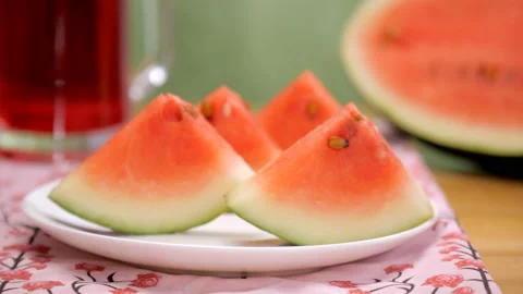 Female taking a bite of a slice of juicy watermelon from the ceramic plate Vídeos de archivo 153200511