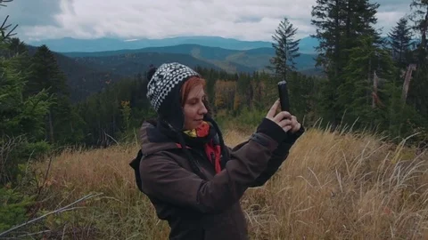 Female taking selfie using her phone in mountains Видео 82824039