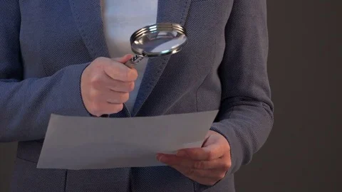 Female tax inspector looking at document with magnifying glass Vídeo Stock 70377307