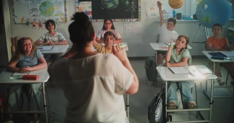 Female Teacher Asking Question. Team of Smart Diverse Kids Raising Hands to Stock Footage 313735778