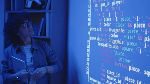 Female Teacher in Dark Classroom Explaining Code on Projection Stock Footage 244701183
