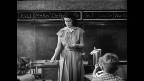 Female Teacher Distributing Notes To Elementary School Students In Classroom Vídeo Stock 157788833