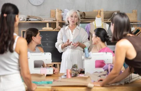 Female teacher explaining pattern structure by chalkboard during sewing course 스톡 사진