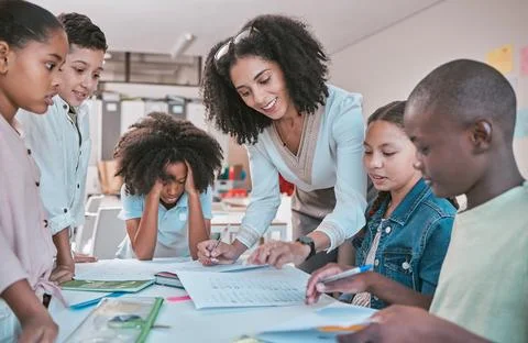 Female teacher helping children with assignment, classroom in school and writing Stock Photos