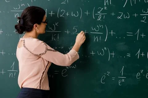 Female teacher standing in front of chalkboard Stock Photos