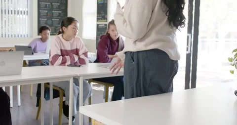 Female teacher standing, turning, gesturing after perching, teaching code with Stock Footage 341029110