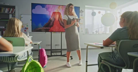 Female Teacher with Tablet Computer Explaining Volcanic Eruption Process to Kids Stock Footage 315536241