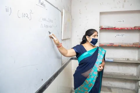 Female Teacher Wearing Mask and teach pointing on whiteboard in classroom, In Stock Photos