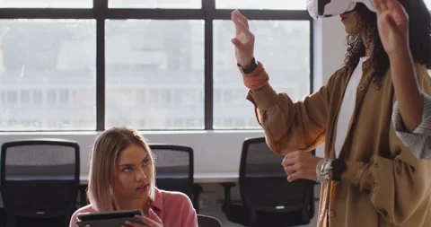 Female team testing VR at work after colleague gesturing woman holding tablet Stock Footage 346178537