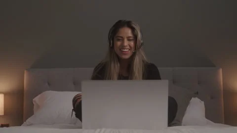 Female Tech Support Sitting On Her Bed While Leading a Virtual Meeting Stock Footage 208784769