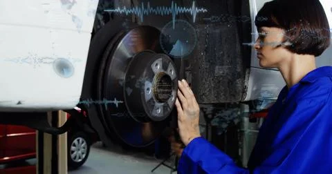 Female technician checking brake rotor after removing wheel, using AR Stock Photos