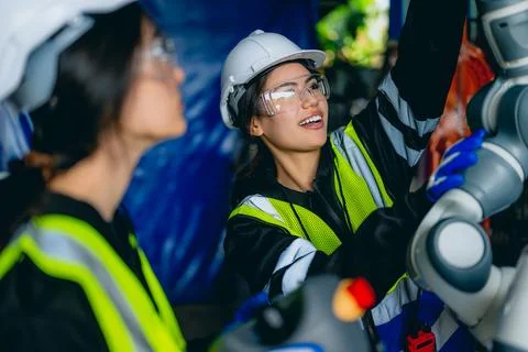 Female technician engineer using controller checking robotic machine Stock Photos