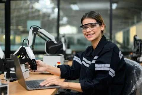 Female technician engineer using laptop checking automatic robotic machine 写真素材