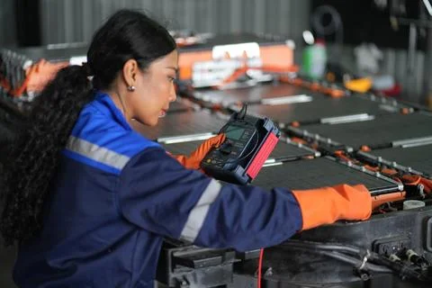 Female Technician Testing Battery Pack in Industrial Assembly Facility Stock Photos