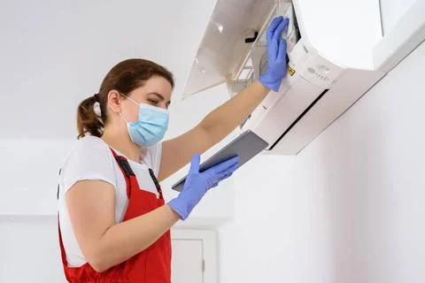 Female technician using digital tablet and repairing air conditioner Femal... Stock Photos