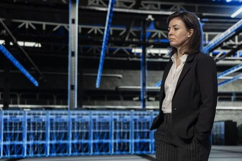 Female technician walking through server farm rows lined with network equipment Stock Photos