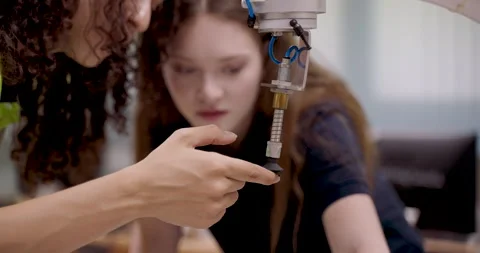 Female technicians observing closely during robotic arm inspection using Stock Footage 316077482