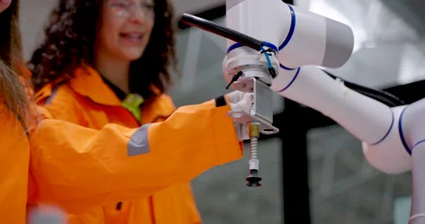 Female technicians working together to install tool on robotic arm during cobot Stock Footage 319476484