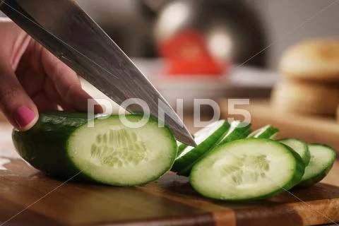 Female teen hand cutting fresh cucumber Stock Photos