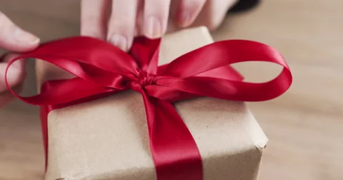 Female teen hands unties the red bow on paper box Stock Footage