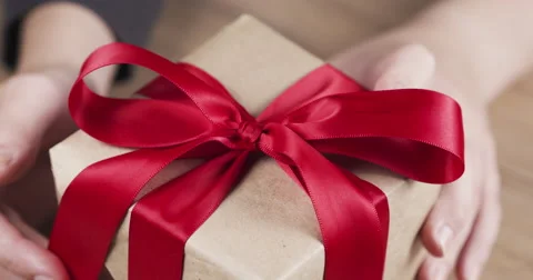 Female teen hands unties the red bow on paper box Stock Footage