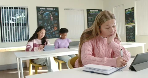 Female teenage students using tablets and taking notes in classroom, camera Stock Footage 340656132