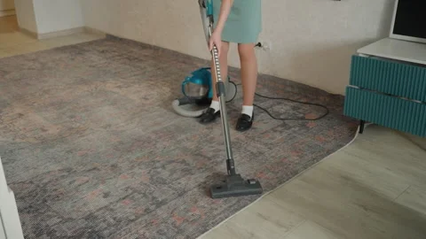 Female tidying patterned living space. Lady sweeping decorative carpet in living Stock Footage 345519961