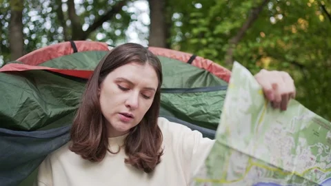 A female tourist exploring the map while sitting in a tent. Opens a new Stock Footage 163274877