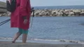 Female tourist with hiking poles in hand stepping down to seacoast, travel HD Footage
