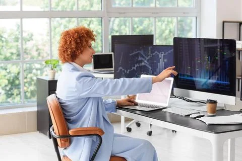 Female trader analyzing financial data on multiple computer screens in a mode Stock Photos