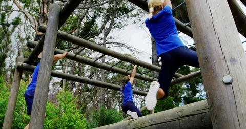 Female trainer clapping hands while fit people climbing monkey bars 4k 動画素材 82244328