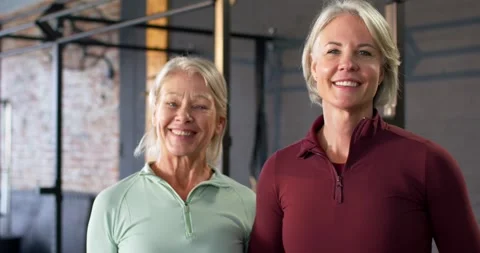 Female trainer coaching while senior woman listening and nodding, both posing in Video stock 342085081