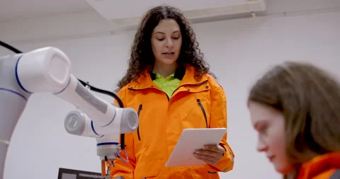 Female trainer instructing young technician on robotic calibration process Stock Footage 313647371