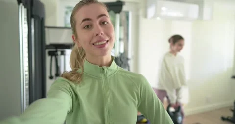 Female trainer introducing workout by pointing to trainee lifting kettlebell in Stock Footage 334999662