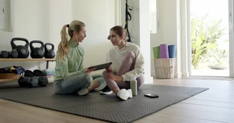 Female trainer tapping tablet while female client nodding to start workout plan Stock Footage 338061642