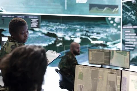 Female trooper checking real time battlefield data in command post Stock Photos