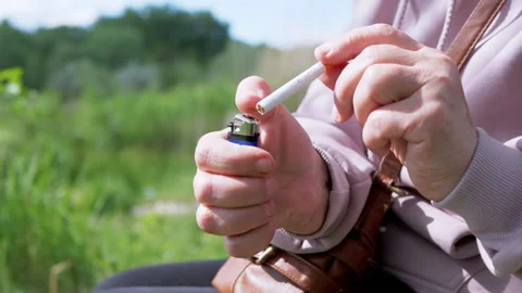 Female is Trying to Light a Cigarette with a Lighter Sitting in Nature on  Sun