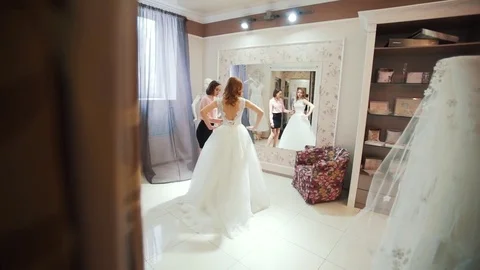 Female trying on wedding dress in a shop with women assistant Stock Footage