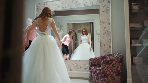 Female trying on wedding dress in a shop with women assistant Stock Footage