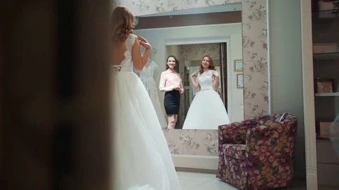 Female trying on wedding dress in a shop with women assistant Stock Footage