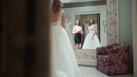 Female trying on wedding dress in a shop with women assistant Stock Footage