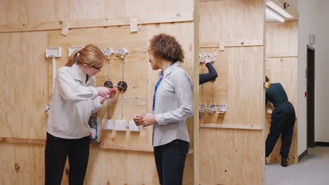 Female Tutor With Trainee Electricians In Workshop Studying For Apprenticeship Stock Footage 130610166