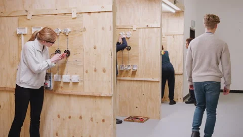 Female Tutor With Trainee Electricians In Workshop Studying For Apprenticeship Stock Footage 130610216