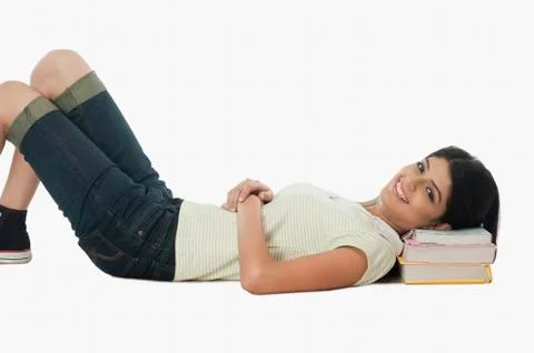 Female university student resting on a stack of books 스톡 사진